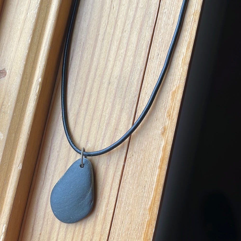 Gray rock pendant necklace with black cord chain.
